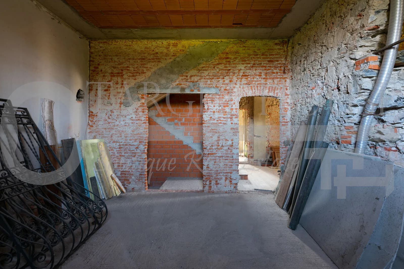 Historic villa near Como renovation interior with exposed brick walls, arched doorways, stone walls, and wooden ceiling