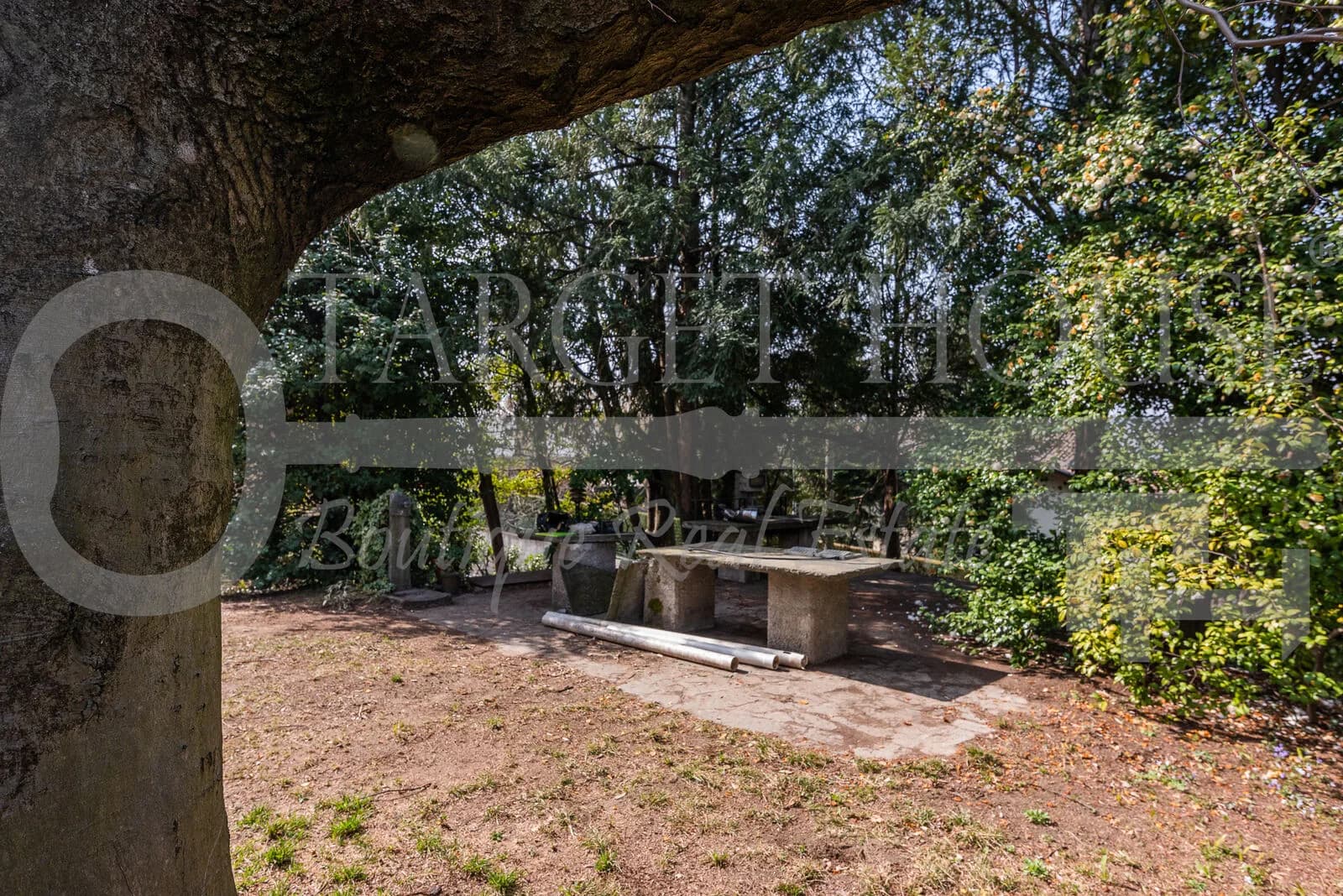 Shaded stone garden table and mature trees in the 1,500 sqm garden of a historic villa near Como