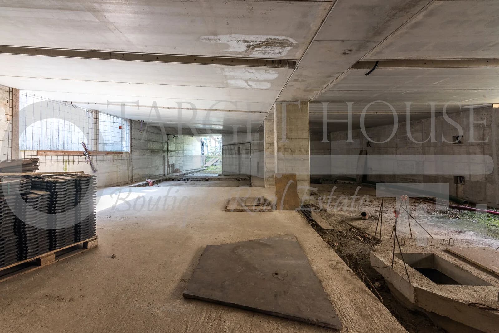 Unfinished basement with concrete ceiling, exposed columns, and construction materials at historic villa near Como